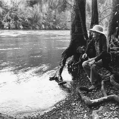 Photograph of Man Sitting by a River