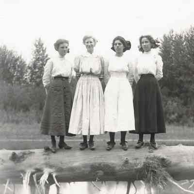 Photograph of four women on a log over the river, Oregon, 1910