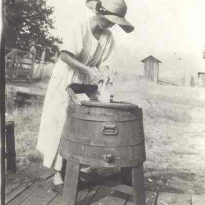 Photograph of unknown women un sun hat doing the wash