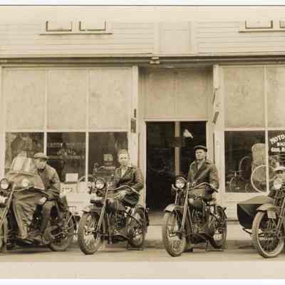 Photograph of motorcyclists posing in front of "Harry [...] Bicycles Moto-Cycles" shop, undated