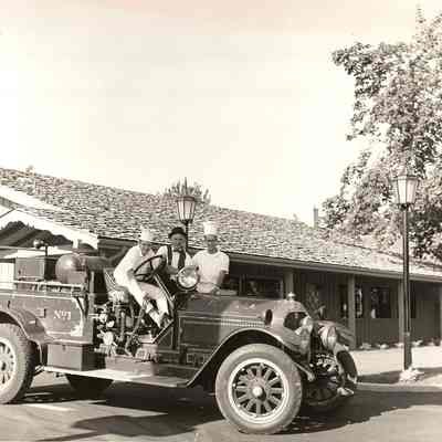 Photograph of Norman Kolln and two unknown men in a firetruck outside Pietro's Pizza, Eugene, Oregon