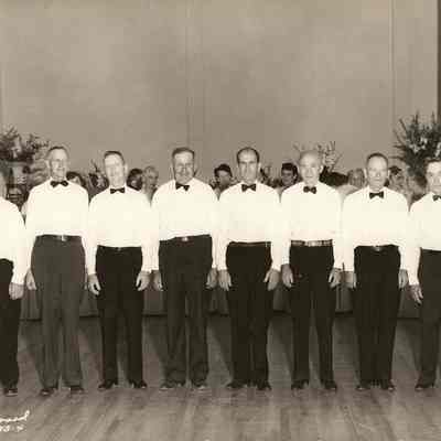 Photograph of a group of 8 men in white shirts and bowties, 1951