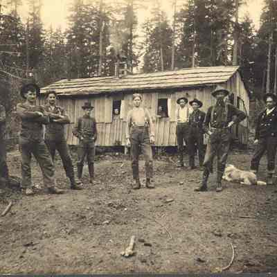 Photograph of nine men and a dog in front of a cookhouse at the William Brothers camp on Rush Island, Oregon, 1901