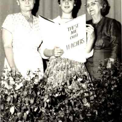 Photograph of teachers Florence Morrison and Mrs. Gregg with student holding presentation book, date unknown.