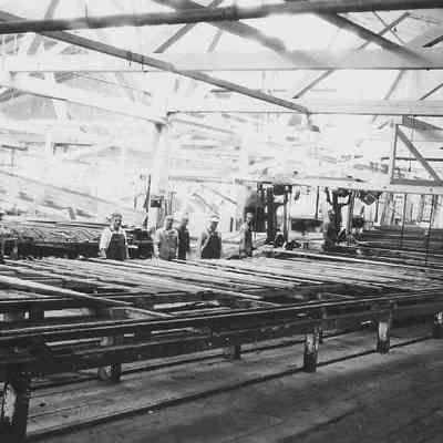 Photograph of eight unknown men inside a lumber mill