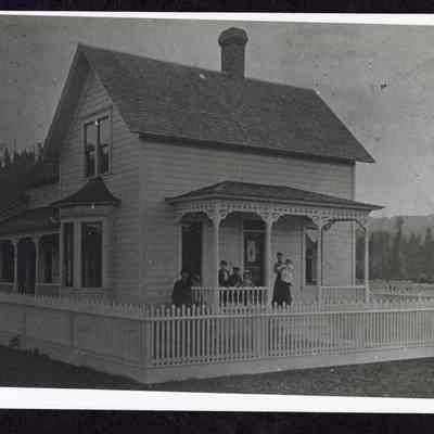 Photograph of an unknown group of seven people on a house porch