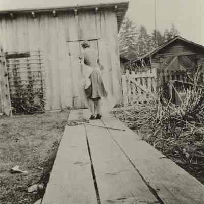 Photograph of unknown women walking toward a shed