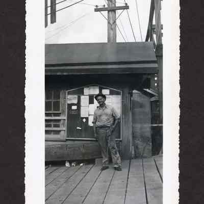 Photograph of unknown man infront of a bulletin board, at Booth Kelly Lumber Co.