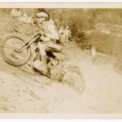 Photograph of Bill Davis senior riding a motorcycle on a hill climb, undated