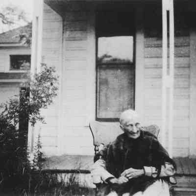 Photograph of Emilia Brattain in front of Brattain/Hadley House, Springfield, OR, date unknown