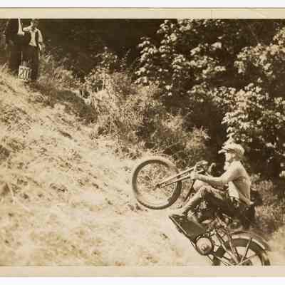 Photograph of Bill Davis senior riding a motorcycle on a hill climb, undated