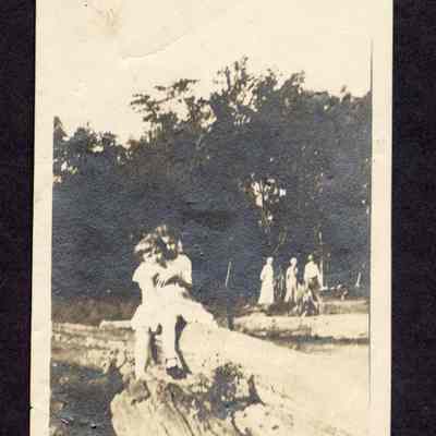 Photograph of two children on a log, undated