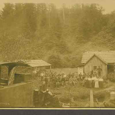 Photograph of Logging Camp with 35 unidentified people and a dog, date 9107-1908