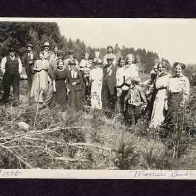 Photograph on postcard of 21 people outside from lodge picnic at Camp Creek School