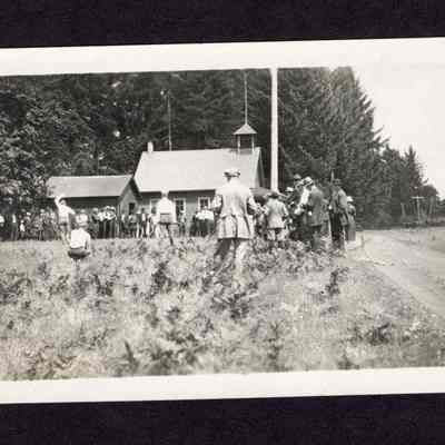 Photograph on postcard of people playing game outside building at lodge picnic at Camp Creek School