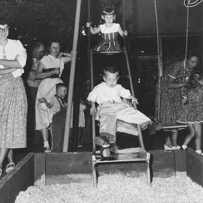 Photograph of children on playground equipment on Main Street during Shoppers Paradise, Springfield, Oregon, 1957