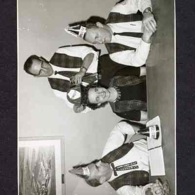 Photograph of 4 unknown people, all wearing matching plaid vests. Possibly 1959.