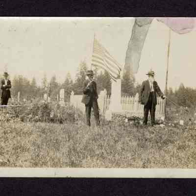 Photograph of three men at a cemetery, undated