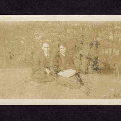 Photograph of unknown woman and man sitting in grass
