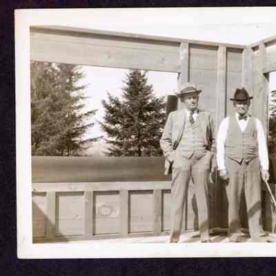 Photograph of two unknown man standing in a frames building, date unknown
