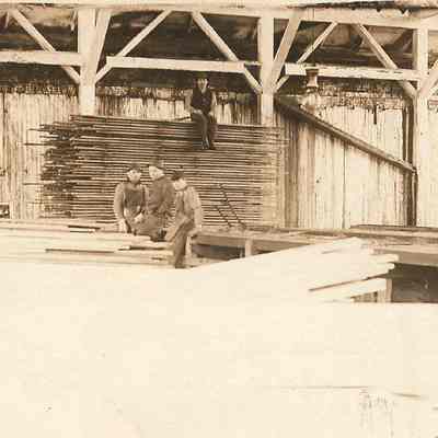 Photograph of four men posed in lumber yard, undated