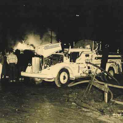 Photograph of white fire truck pumping from hydrant at night, Winlock Handle Factory fire, Springfield, Oregon, 1950.