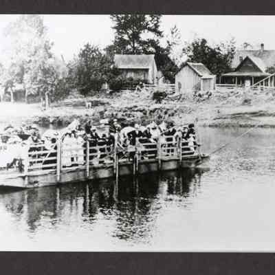 Photograph of a large group of unknown people on a ferry crossing a river
