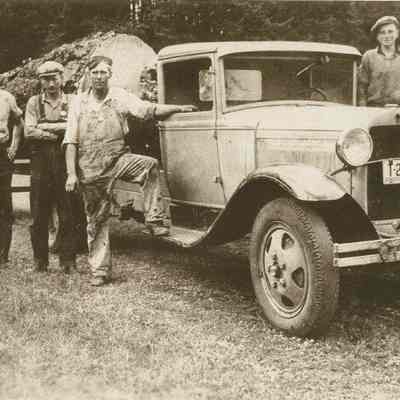 Photograph of five people standing around a truck carrying a large log, Upper Camp Creek, Oregon, circa 1930s