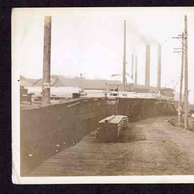 Photograph on postcard of first roadway going under Jones Lumber Mill, Portland Oregon, date unknown