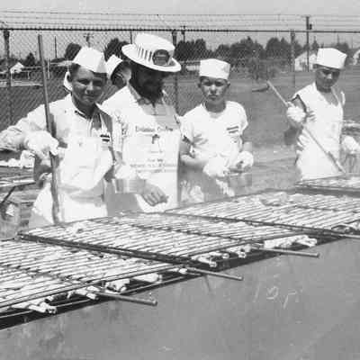 Photograph of unknown men broiling chicken, 1957