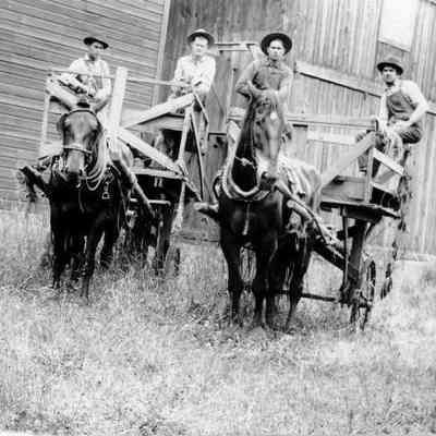 Photograph of four hop yard workers on two horse drawn wagons