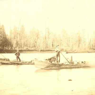 Photograph of two unidentified men in boats on river