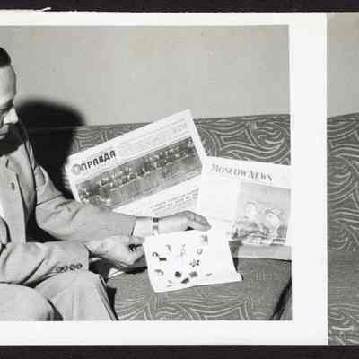 Photograph of a man and Russian newspapers, unknown date and location