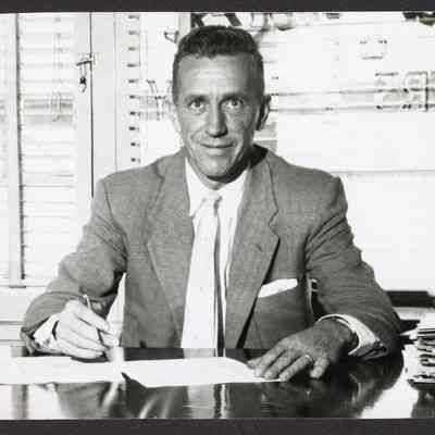 Photograph of unknown man signing papers, undated