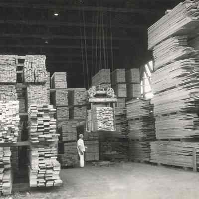 Photograph of Man and Machine Stacking Lumber, Date Unknown
