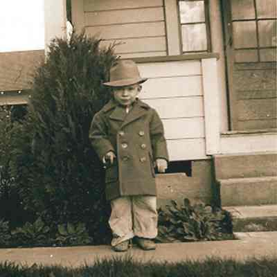 Photograph of Bob Berg standing in front of a house, undated