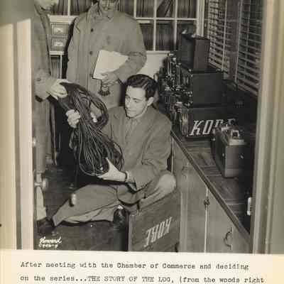 Photograph of three men in suits at KORE packing up cables, Eugene, Oregon, circa 1945-1951