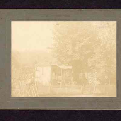Photograph of an unknown house with three people on the porch