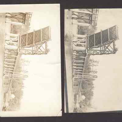 Photograph of drawbridge, up with two men on top of tower. Date unknown.