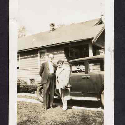 Photograph of a man and woman in front of a house and car, circa 1920