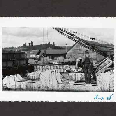 Photograph of unknown men loading bridge parts onto a train, 1948