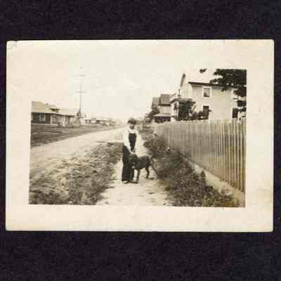 Photograph of a boy and a dog on a sidewalk