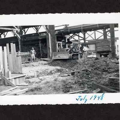 Photograph of with three unknown men, and one in a caterpillar tractor during the drainage construction at the Booth-Kelly Lumber Mill, Springfield, Oregon, 1948
