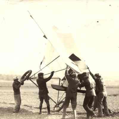 Photograph of 7 unknown men around an early aircraft