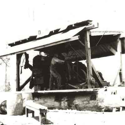 Photograph of man working at a vertical steam donkey