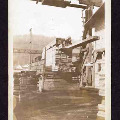 Photograph on postcard of a truck loaded with wood under a craneway, Portland, Oregon, date unknown