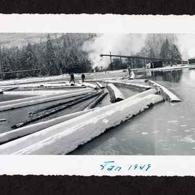 Photograph of two people on a frozen log in a log pond