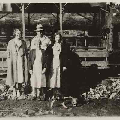Photograph of group of three women and a man standing by railcar