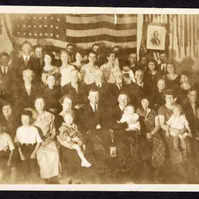 Photograph of a large group in front of American Flag, unknown date and location
