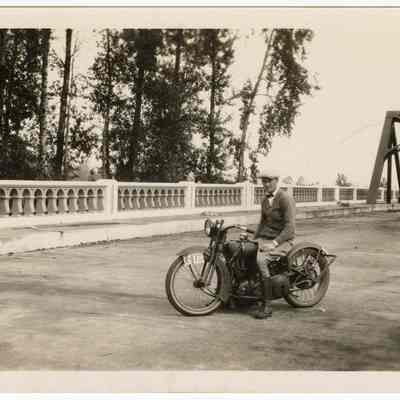 Photograph of Bill Davis on a motorcycle, truss bridge in Springfield, 1926
